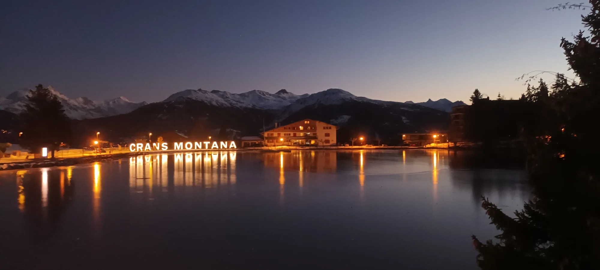 Crans-Montana iluminada de noche junto al lago